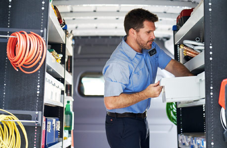 A man standing and working in the back of a Cargo Van